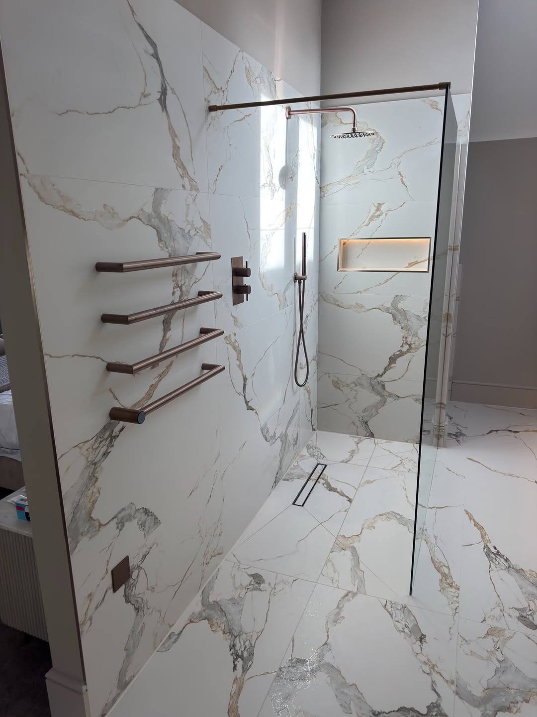 Marble walk-in shower with a bronze towel rail